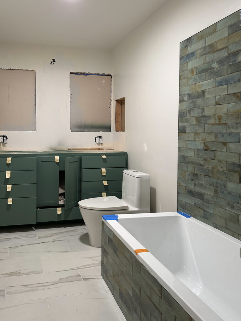 green vanity, green and blue tile, white tub and toilet