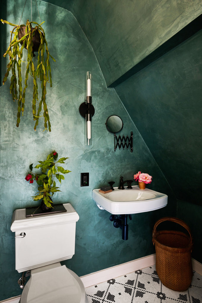 green bathroom wall, wall mounted sink, mosaic tile, hanging plant in corner