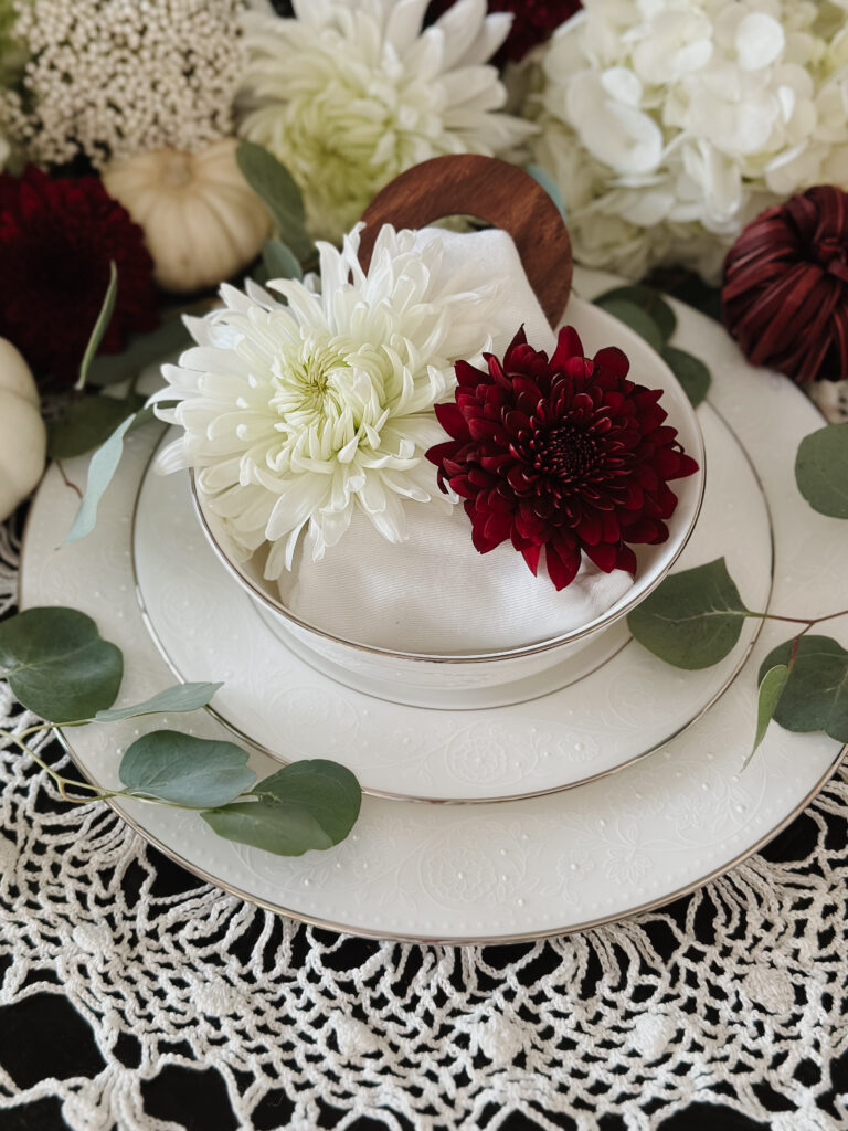 White and red flowers in bowl, white silver china, table setting, green leaves